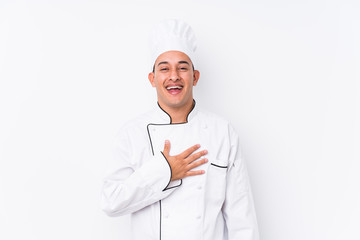 Young latin chef man isolated laughs out loudly keeping hand on chest.
