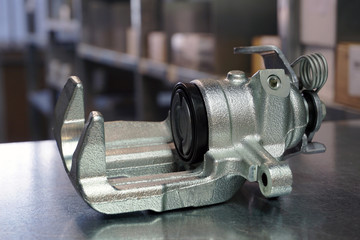 Front brake caliper close-up on a steel background. Original high-quality spare parts for a modern...