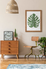 Vintage interior design of living room with stylish retro chair and commode, pendant lamp, plants, cacti, black clock and brown mock up poster frame on the beige wall. Stylish home decor. Template. 