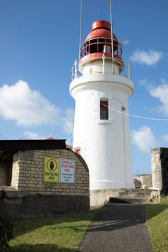 lighthouse painted white with blue sky and white clouds in the background