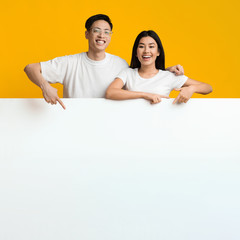 Asian lovers leaning on big blank board for advertisement