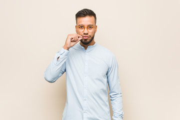 Young south-asian business man with fingers on lips keeping a secret.