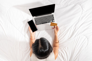 Top view of a woman using a mobile phone and credit card for shopping online. Blank on the laptop and empty space on smart phone