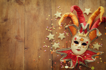 Gold and red elegant traditional Venetian jester mask over old wooden background © tomertu