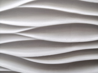 Abstract background formed by smooth wavy lines of gypsum on the wall. The difference of lights and shadows.