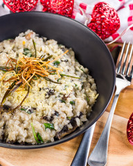 A serving of Mushroom Risotto in a dark round bowl, surrounded by a red and white cloth and red love heart shaped  string lights.