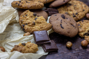 Freshly baked American chocolate chip cookies on rustic black metal table background.