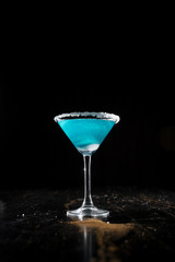 the bartender prepares a blue cocktail along the edges of the salt, throws lemon slices into the cocktail, splashes fly