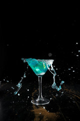 the bartender prepares a blue cocktail along the edges of the salt, throws lemon slices into the cocktail, splashes fly