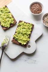 Healthy Snack from Wholegrain Rye Crispbread Crackers with Avocado on white marble background with copy space