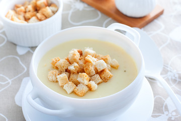 Mashed potato soup with homemade croutons in a white soup plate, horizontal
