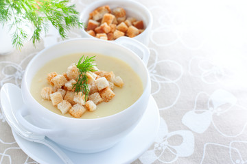 Mashed potato soup with homemade croutons of white bread in a white soup plate, horizontal, copy space