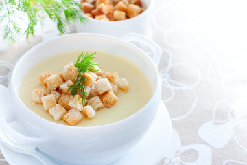 Mashed potato soup with homemade croutons of white bread in a white soup plate, horizontal, copy space