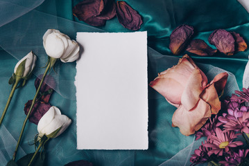 Wedding invitation mockup with roses, papers on white textile background. Top view, flat lay. Wedding stationary. Perfect for presentation of your invitation, menu, greeting cards