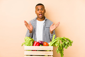 Young farmer man isolated on a beige background surprised and shocked.