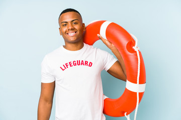 Young latin life guard isolated on blue background happy, smiling and cheerful.