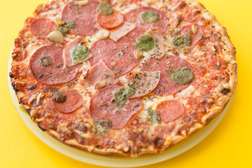 Pizza on a plate on a yellow background.