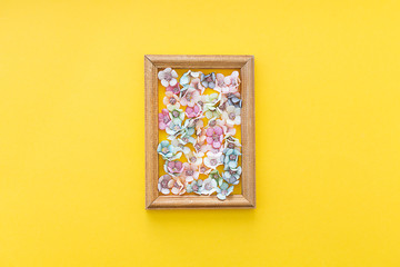 Small colorful flowers in a frame on a yellow background.