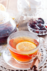 Black tea with cinnamon and lemon in a glass cup on a wooden table, selective focus