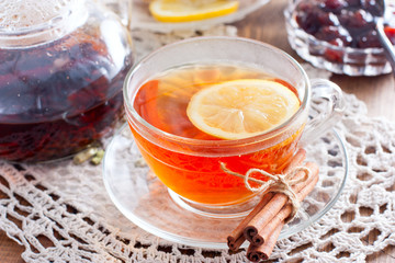 Black tea with cinnamon and lemon in a glass cup on a wooden table, horizontal