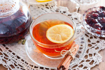 Black tea with cinnamon and lemon in a glass cup on a wooden table, horizontal