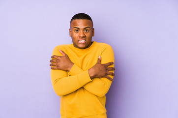Young latin man isolated on purple background going cold due to low temperature or a sickness.