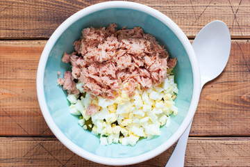 Fototapeta na wymiar Step by step preparation of salad with canned tuna and corn, step 5 - adding canned tuna fillet to the salad, top view, horizontal