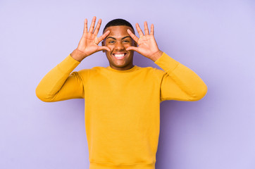 Young latin man isolated on purple background keeping eyes opened to find a success opportunity.