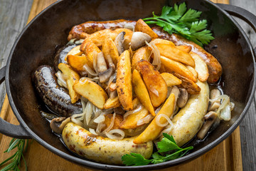 grilled sausages, potatoes and sauerkraut on cooking pan