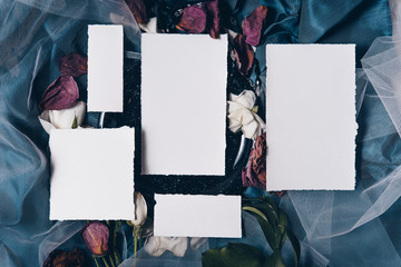 Wedding invitation mockup with old black plate, roses, papers on silk blue background. Top view, flat lay. Wedding stationary. Perfect for presentation of your invitation, menu, greeting cards