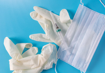 Medical mask, gloves and syringe isolated on a blue background