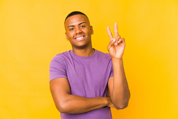 Young latin man isolated on yellow background showing number two with fingers.