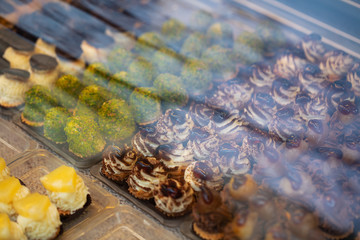 Various fresh pastries and desserts are on display in a bakery shop