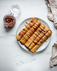 french crepe filled with caramel fudge and decorated with chocolate fudge, berries castor sugar and mint leaves on marble background with copy space