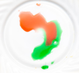 Red and green paint on a white plate.