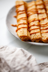 french crepe filled with caramel fudge and decorated with chocolate fudge, berries castor sugar and mint leaves on marble background with copy space