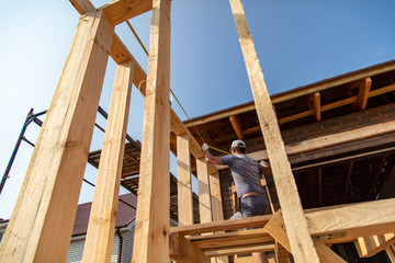 A worker measures a wooden workpiece with a meter.