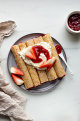 french crepe filled with caramel fudge and decorated with chocolate fudge, berries castor sugar and mint leaves on marble background with copy space