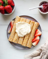 french crepe filled with caramel fudge and decorated with chocolate fudge, berries castor sugar and mint leaves on marble background with copy space