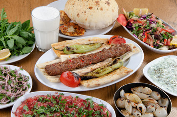 Traditional Turkish Adana kebab or kebap meat food, appetizers, ayran and salgam on table from top view in turkish restaurant.