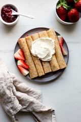 french crepe filled with caramel fudge and decorated with chocolate fudge, berries castor sugar and mint leaves on marble background with copy space
