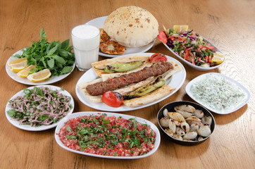Traditional Turkish Adana kebab or kebap meat food, appetizers, ayran and salgam on table from top view in turkish restaurant.