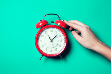 Alarm clock on the color background. A hand of person switching off an alarm clock in the morning