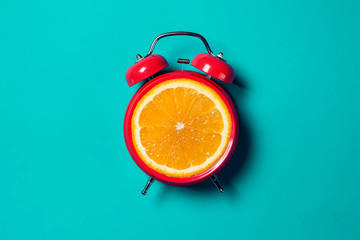 Alarm clock with orange fruit on the place of watch dial.