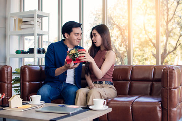 An asian man is giving a gift to his girlfriend