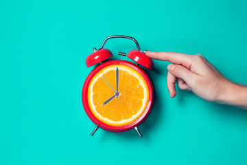 Alarm clock with orange fruit on the place of watch dial.