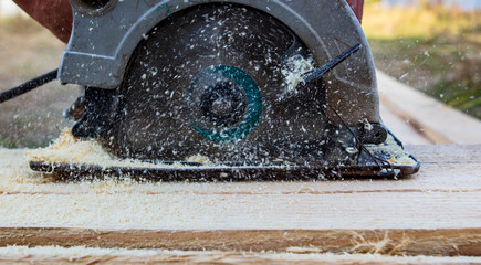 A worker saws a wooden beam.