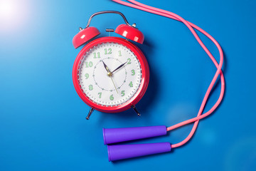 Alarm clock and jump rope on the color background. Fitness and healthcare concept