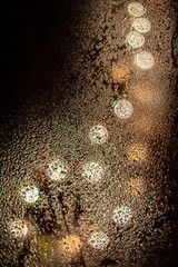 Blurred gold lights behind wet glass
