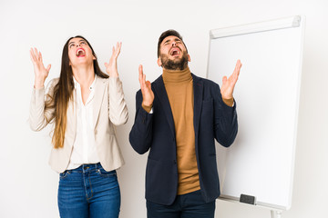 Young caucasian business couple isolated screaming to the sky, looking up, frustrated.